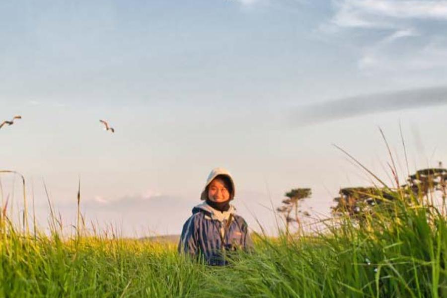 Cover of Enveloep Magazine 2022 - 2023 edition with person in background of photo of grass and bird flying overhead